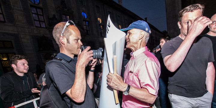 Der Teilnehmer einer Pegidademonstration in München hindert einen Journalisten beim fotografieren